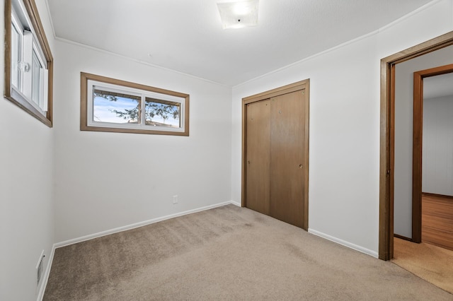 unfurnished bedroom with light colored carpet and a closet