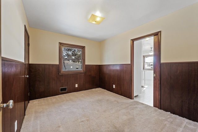 spare room with wood walls and light carpet