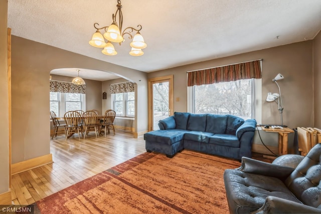 living room with a textured ceiling, light wood-type flooring, radiator heating unit, and an inviting chandelier