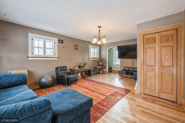 living room featuring a chandelier, a textured ceiling, and light wood-type flooring