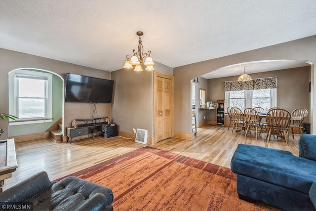 living room with a textured ceiling, hardwood / wood-style flooring, and a notable chandelier