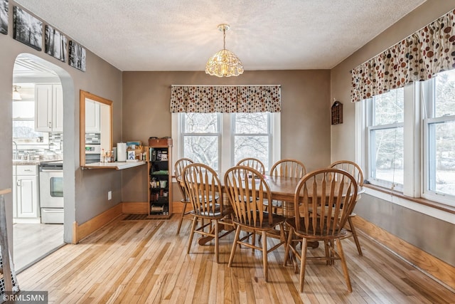 dining area featuring a textured ceiling, light wood-type flooring, and a notable chandelier