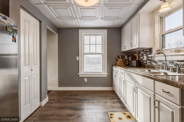 kitchen featuring white cabinets, plenty of natural light, dark hardwood / wood-style floors, and stainless steel refrigerator