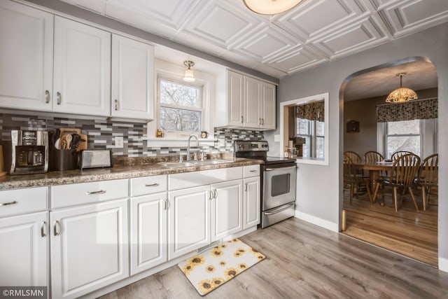 kitchen with decorative backsplash, stainless steel range with electric stovetop, sink, light hardwood / wood-style flooring, and white cabinetry