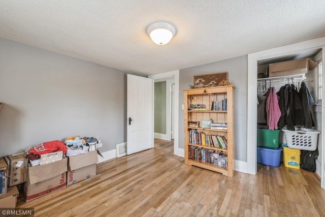 miscellaneous room with light wood-type flooring and a textured ceiling