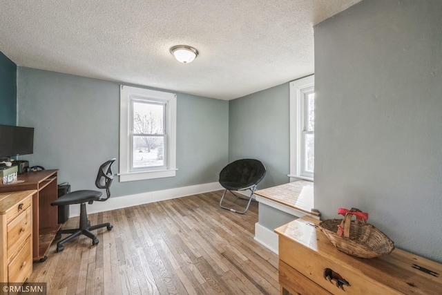 home office with light hardwood / wood-style floors and a textured ceiling