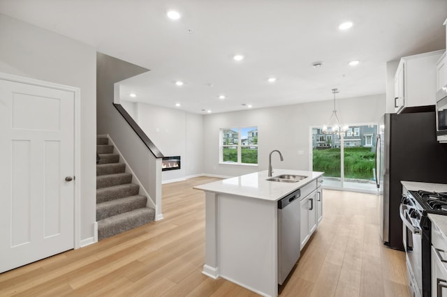 kitchen featuring white cabinets, sink, light wood-type flooring, an island with sink, and appliances with stainless steel finishes