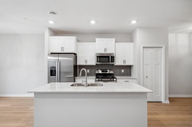 kitchen featuring sink, white cabinets, stainless steel appliances, and a center island with sink