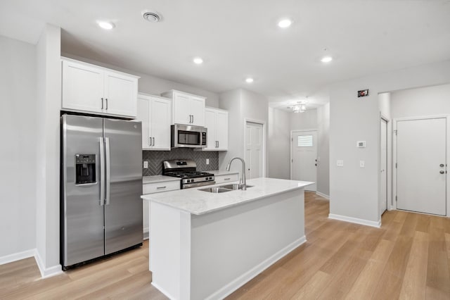 kitchen with white cabinetry, sink, light hardwood / wood-style flooring, a kitchen island with sink, and appliances with stainless steel finishes