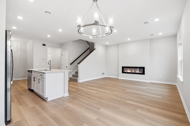 kitchen featuring appliances with stainless steel finishes, light wood-type flooring, and decorative light fixtures