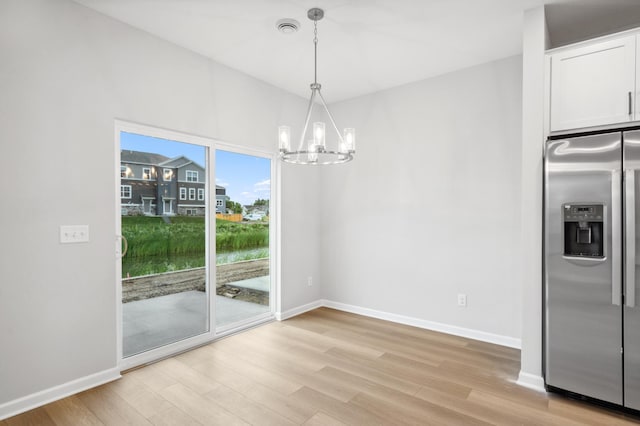 unfurnished dining area with light hardwood / wood-style floors and a notable chandelier