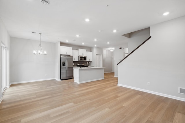 unfurnished living room featuring light wood-type flooring, a notable chandelier, and sink