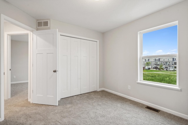 unfurnished bedroom featuring a closet, light carpet, and multiple windows