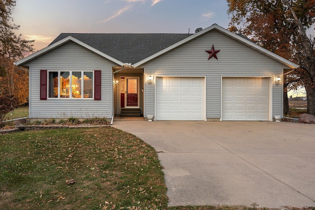 ranch-style house featuring entry steps, a shingled roof, a lawn, concrete driveway, and an attached garage