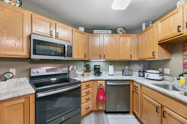 5650 Boone Ave N Unit 321, New Hope, MN 55428 - kitchen with stainless steel appliances, a textured ceiling, light wood-style floors, and light stone countertops