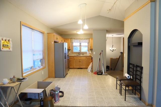 kitchen featuring light brown cabinets, stainless steel refrigerator, hanging light fixtures, and lofted ceiling