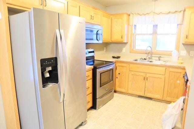 kitchen featuring appliances with stainless steel finishes, light brown cabinetry, and sink