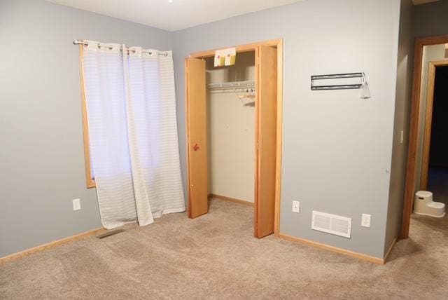 unfurnished bedroom with light colored carpet and a closet