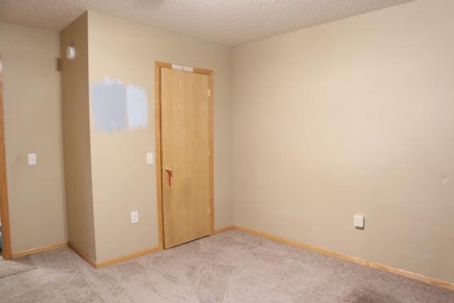 unfurnished bedroom featuring a textured ceiling, light colored carpet, and a closet