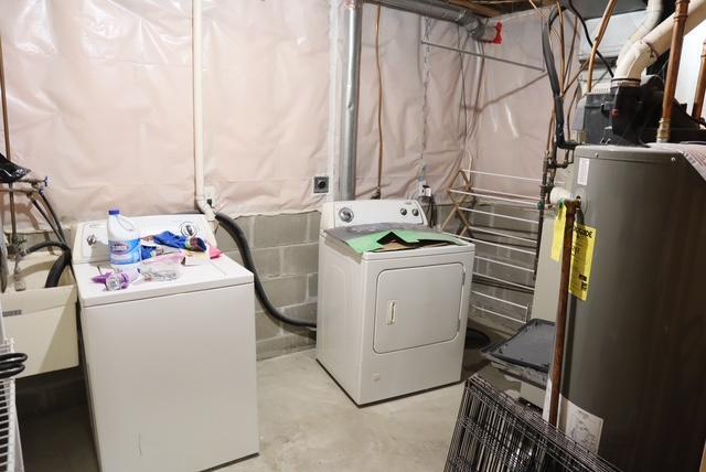 laundry area featuring washer and dryer, laundry area, water heater, and concrete block wall