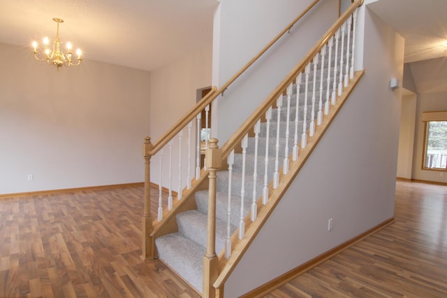 stairs with hardwood / wood-style floors and an inviting chandelier