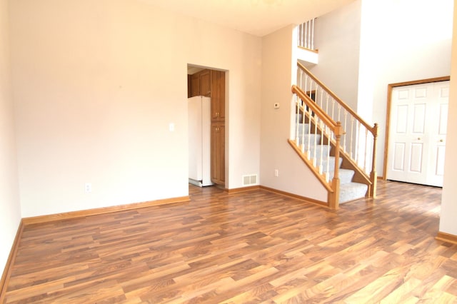 empty room with a high ceiling and hardwood / wood-style flooring