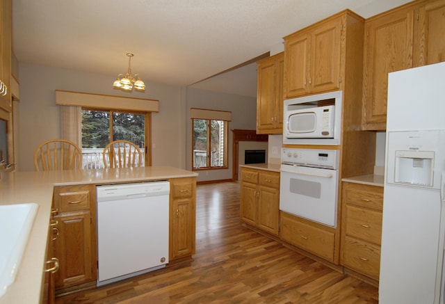 kitchen featuring white appliances, light hardwood / wood-style floors, pendant lighting, a wealth of natural light, and an inviting chandelier