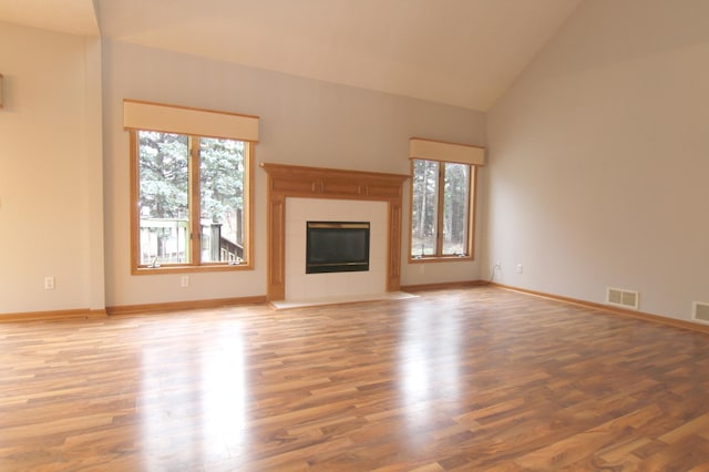 unfurnished living room with a fireplace, high vaulted ceiling, and wood-type flooring