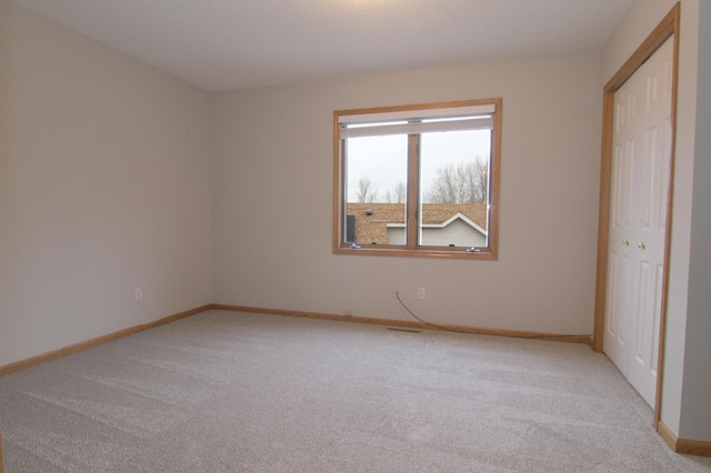 unfurnished bedroom with a closet and light carpet