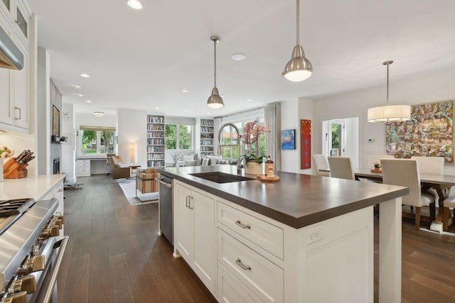 kitchen featuring white cabinetry, hanging light fixtures, dark wood-type flooring, and sink