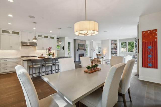 dining space with a large fireplace, dark hardwood / wood-style floors, and an inviting chandelier