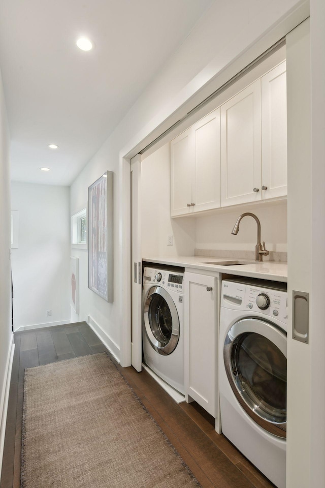 laundry area featuring cabinets, dark hardwood / wood-style flooring, sink, and washing machine and clothes dryer