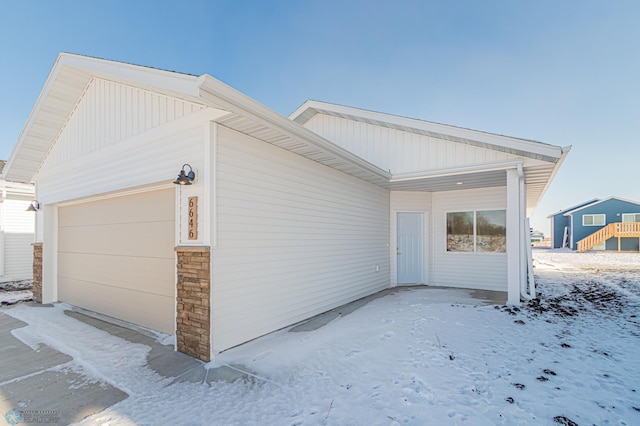 snow covered property with a garage