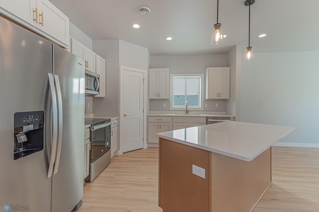 kitchen featuring sink, a kitchen island, light hardwood / wood-style flooring, white cabinets, and appliances with stainless steel finishes