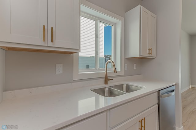 kitchen featuring dishwasher, sink, white cabinets, and light hardwood / wood-style flooring