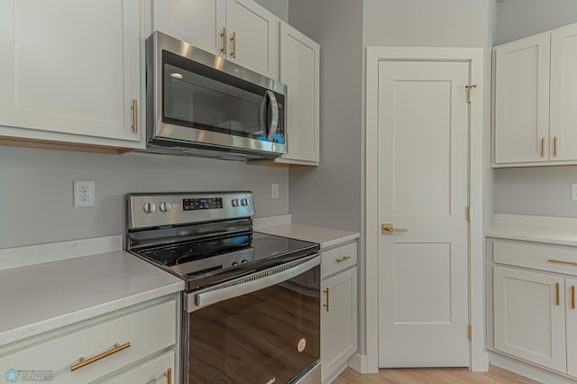 kitchen featuring stainless steel appliances, white cabinetry, and light hardwood / wood-style flooring