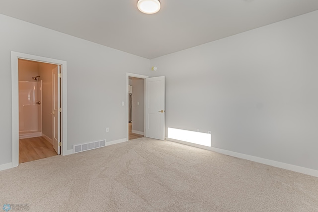 unfurnished bedroom with connected bathroom and light carpet