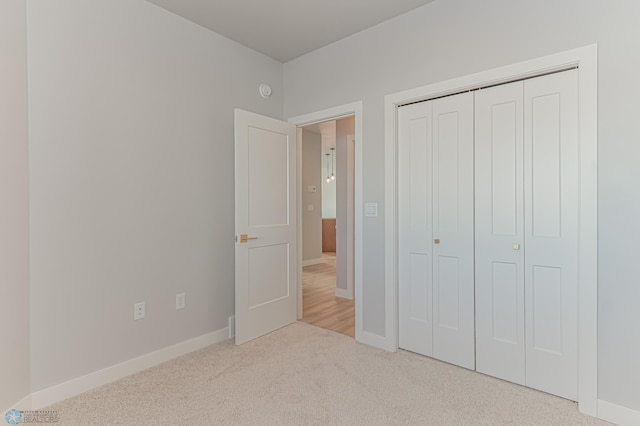 unfurnished bedroom with light carpet and a closet