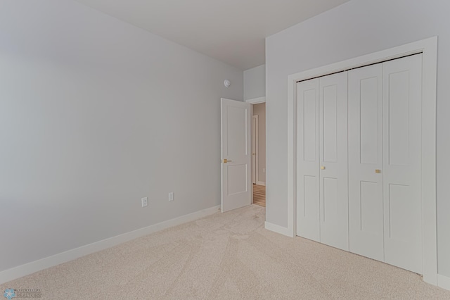 unfurnished bedroom featuring light colored carpet and a closet