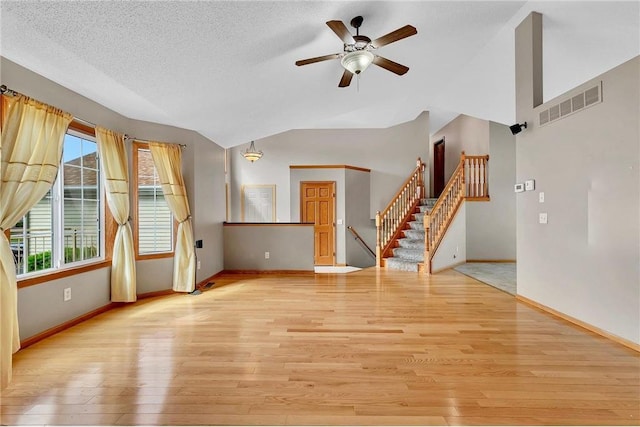 unfurnished living room featuring vaulted ceiling, ceiling fan, a textured ceiling, and light wood-type flooring