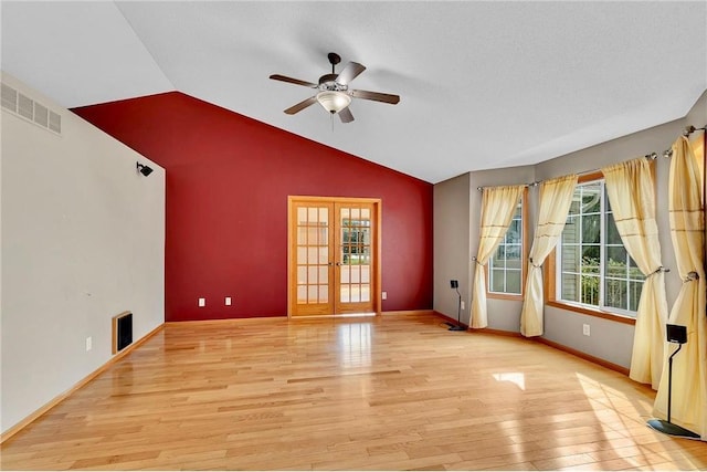 unfurnished living room with ceiling fan, french doors, light hardwood / wood-style flooring, a textured ceiling, and vaulted ceiling