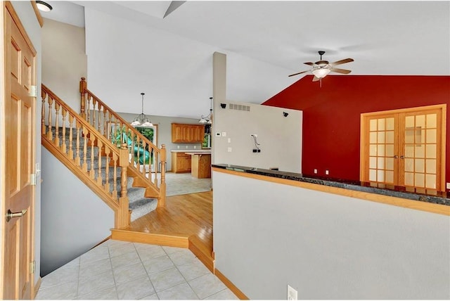 interior space featuring vaulted ceiling, french doors, ceiling fan with notable chandelier, and hardwood / wood-style flooring