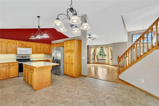 kitchen featuring appliances with stainless steel finishes, ceiling fan with notable chandelier, light hardwood / wood-style floors, a kitchen island, and hanging light fixtures