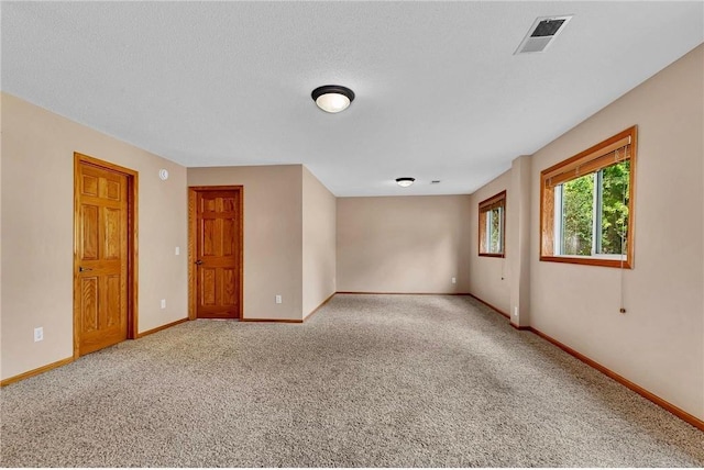 unfurnished room with a textured ceiling and light carpet