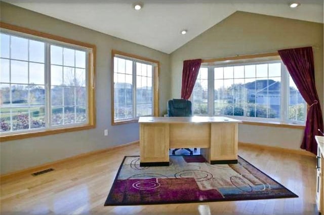 home office with a healthy amount of sunlight, lofted ceiling, and light hardwood / wood-style floors