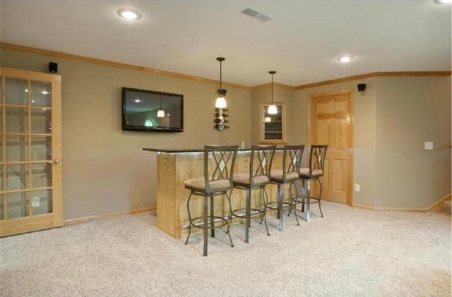 bar featuring light colored carpet, hanging light fixtures, and crown molding