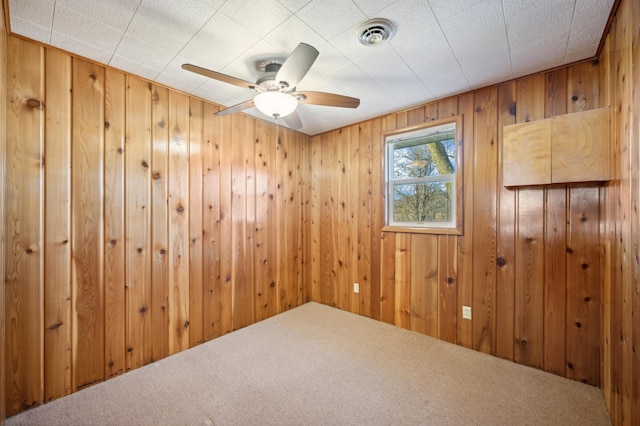 unfurnished room featuring carpet floors, ceiling fan, and wood walls