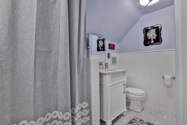 bathroom with vaulted ceiling, vanity, tile walls, and toilet