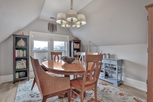 dining area featuring a chandelier, light hardwood / wood-style flooring, and vaulted ceiling