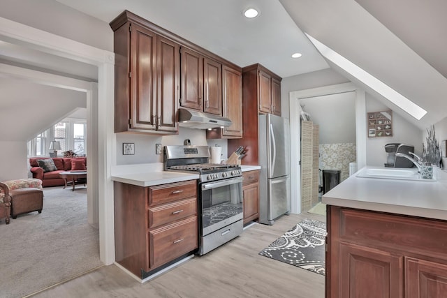 kitchen with vaulted ceiling with skylight, sink, stainless steel appliances, and light hardwood / wood-style flooring